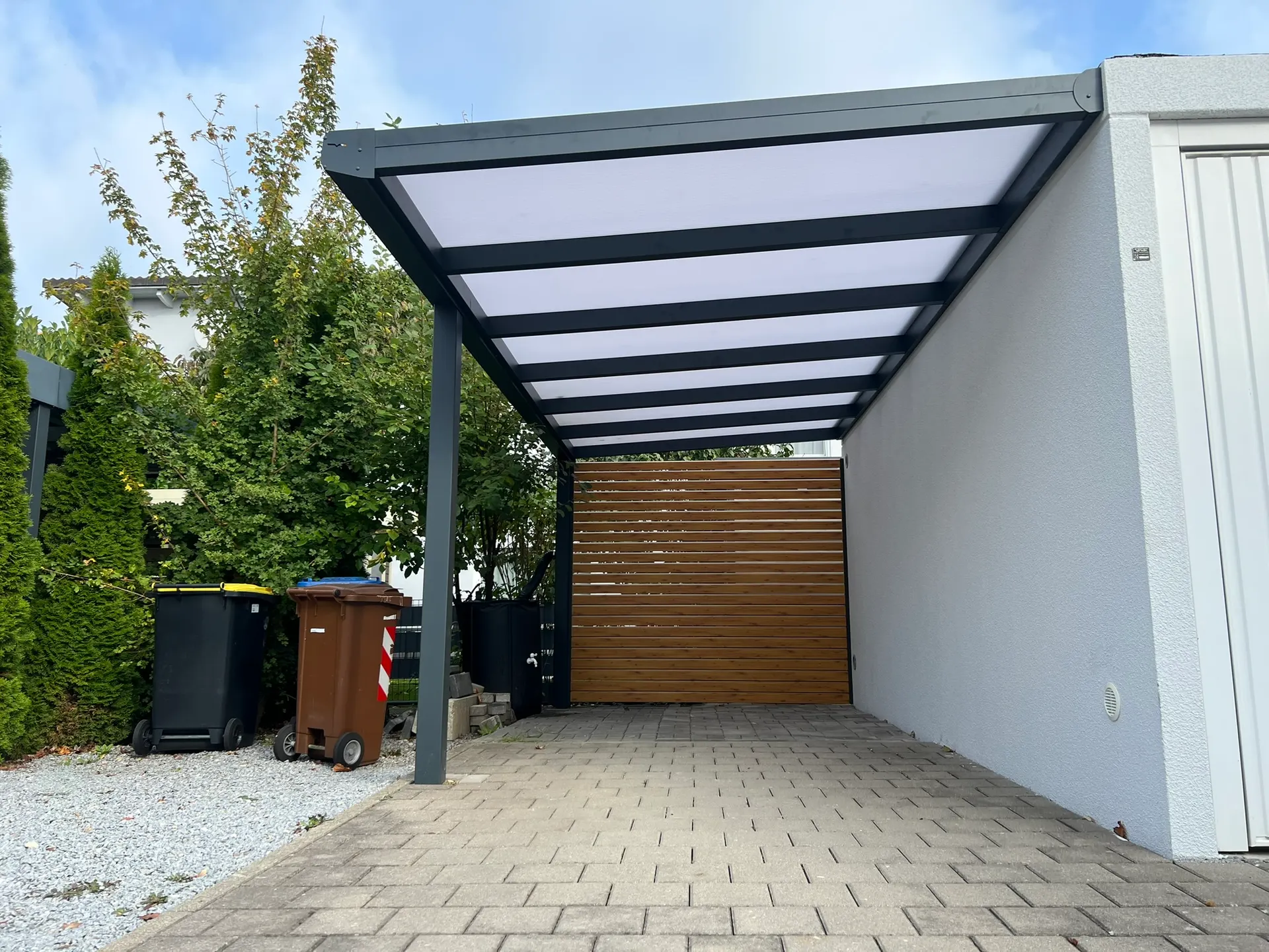 Carport mit Wandanschluss aus Aluminium in Gersthofen mit Polycarbonat-Dach und Seitenwand in Holzoptik
